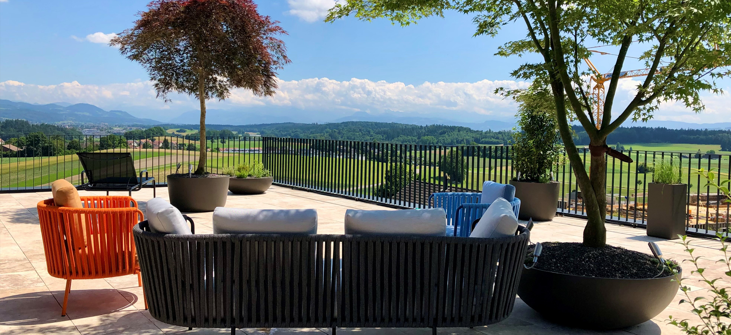 Sonnige Terrasse mit Schattenbäumen und Aussicht